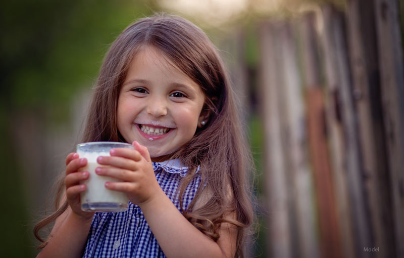 Little girl drinking milk with a huge smile on her face.